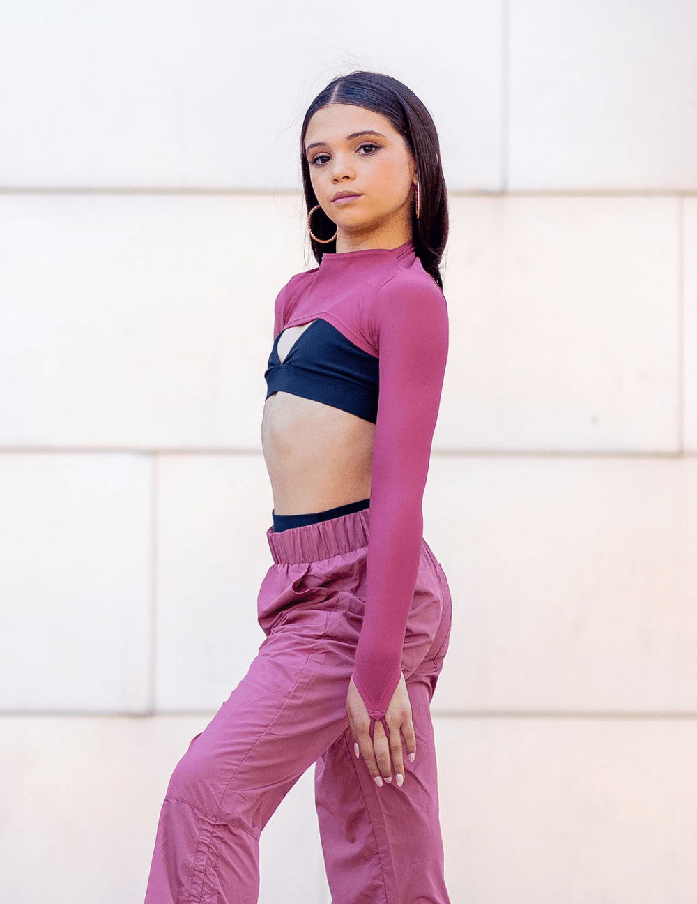 Woman wearing a pink athletic outfit with a white wall background