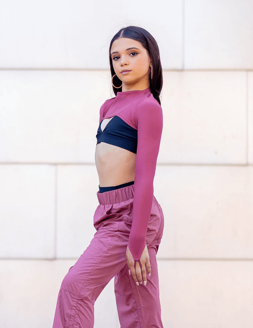 Woman wearing a pink athletic outfit with a white wall background