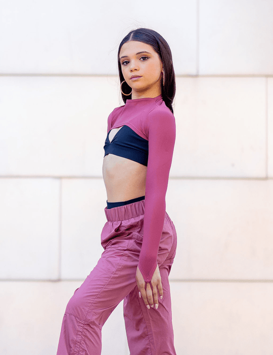 Woman wearing a pink athletic outfit with a white wall background