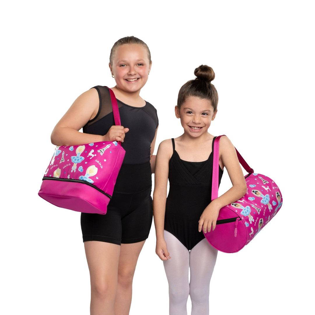 Two young girls holding pink duffel bags with colorful designs on a white background