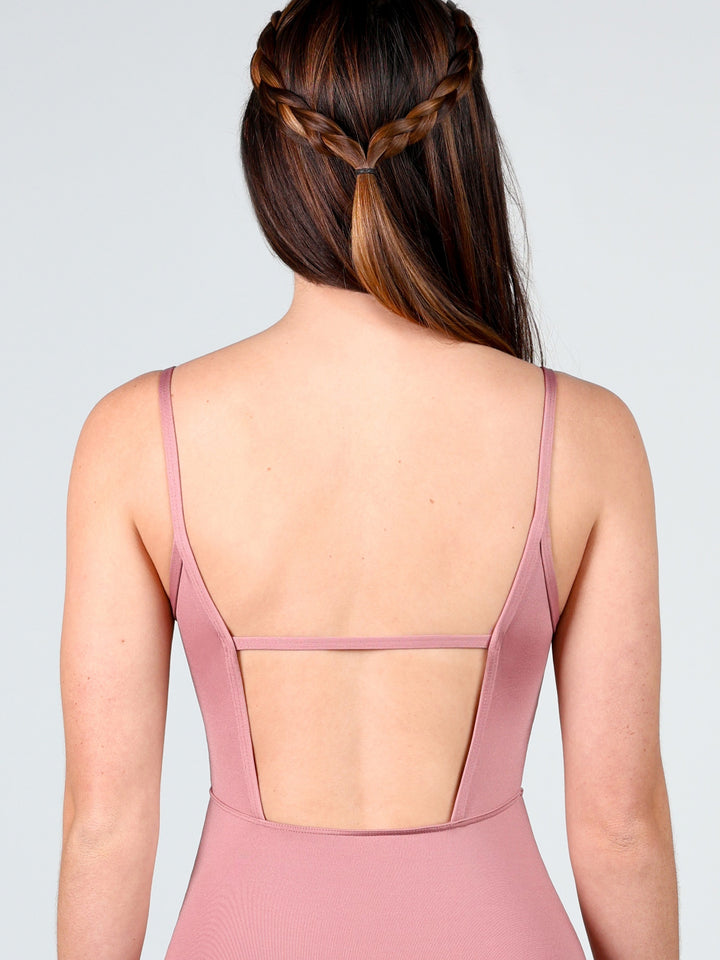 Woman wearing a pink dress with a backless design on a plain background