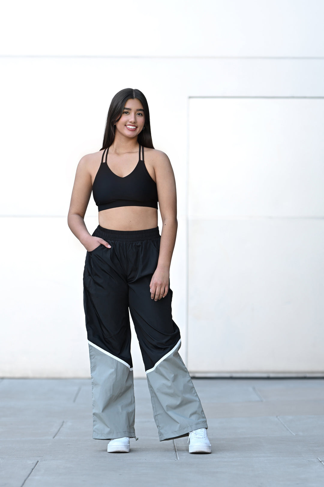 Woman wearing a black sports bra and high-waisted pants with a white background