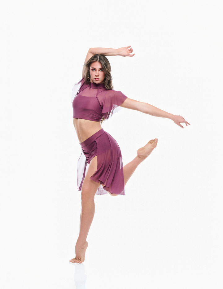 Dancer in a purple outfit posing on a white background