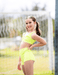 Young girl in a bright yellow sports outfit standing outdoors with a blurred background