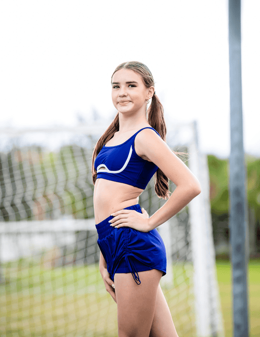 Young woman in a blue athletic outfit standing outdoors with a blurred background
