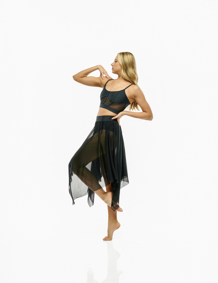A blonde model wearing a black sheer mesh dance crop top and matching high-waisted flowing skirt, posing on a seamless white studio background.