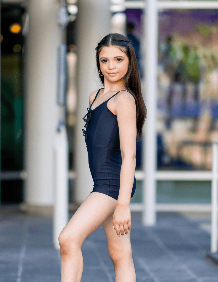 Woman in a black swimsuit standing outdoors with blurred background