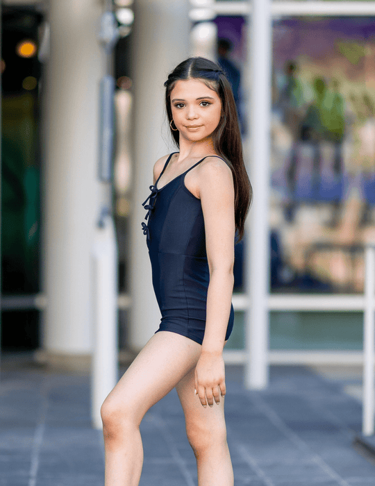 Woman in a black swimsuit standing outdoors with blurred background