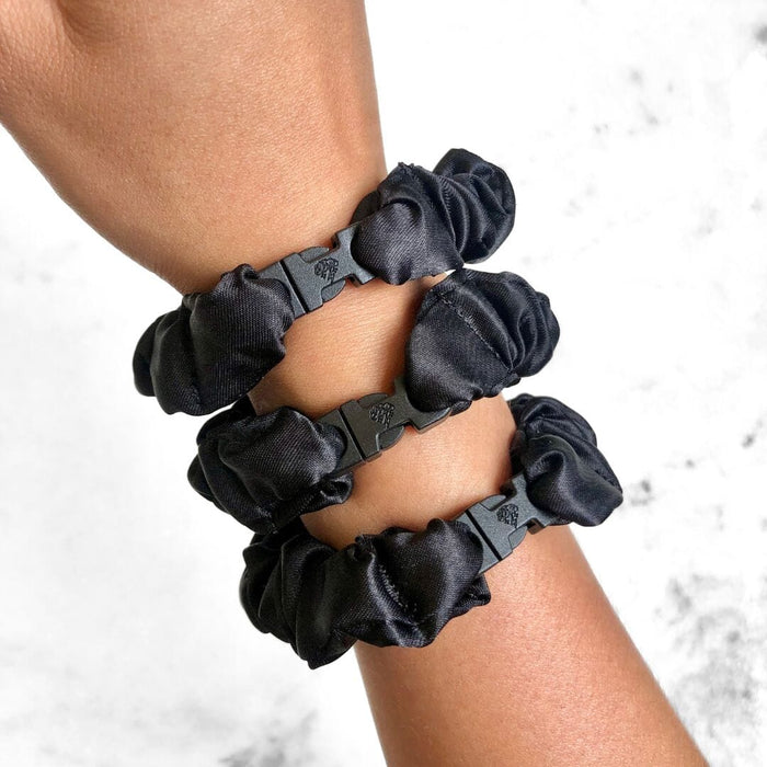 Black scrunchies on a wrist against a light background