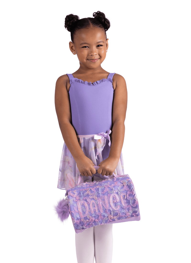 Young girl in a purple outfit holding a matching bag on a white background