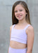 Young girl wearing a light purple sports bra and shorts against a neutral background