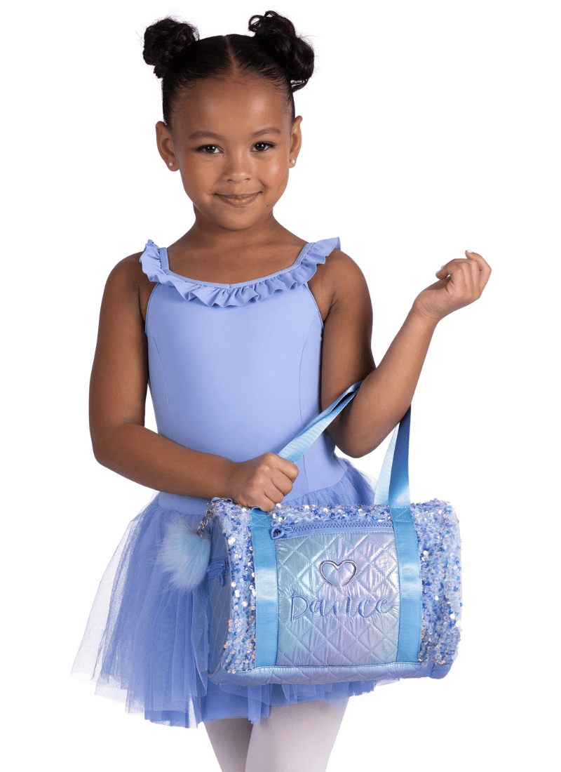 Young girl in a blue dress holding a matching bag on a white background