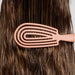 Person using a pink wide-tooth comb on their brown hair against a neutral background