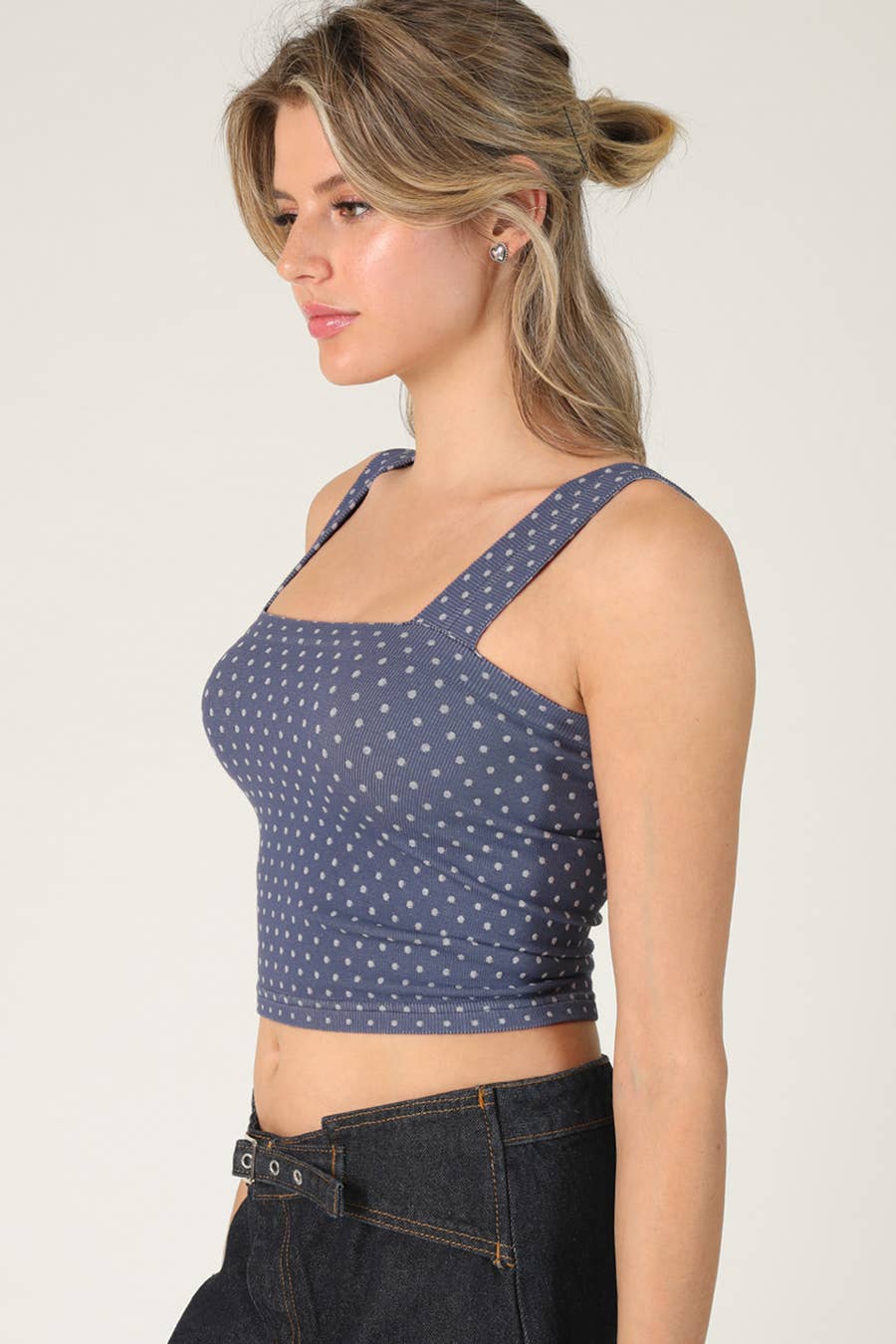 Woman wearing a blue polka dot crop top against a plain background
