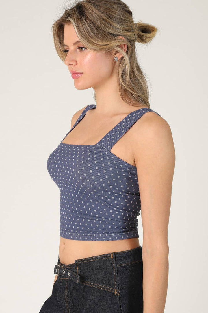 Woman wearing a blue polka dot crop top against a plain background