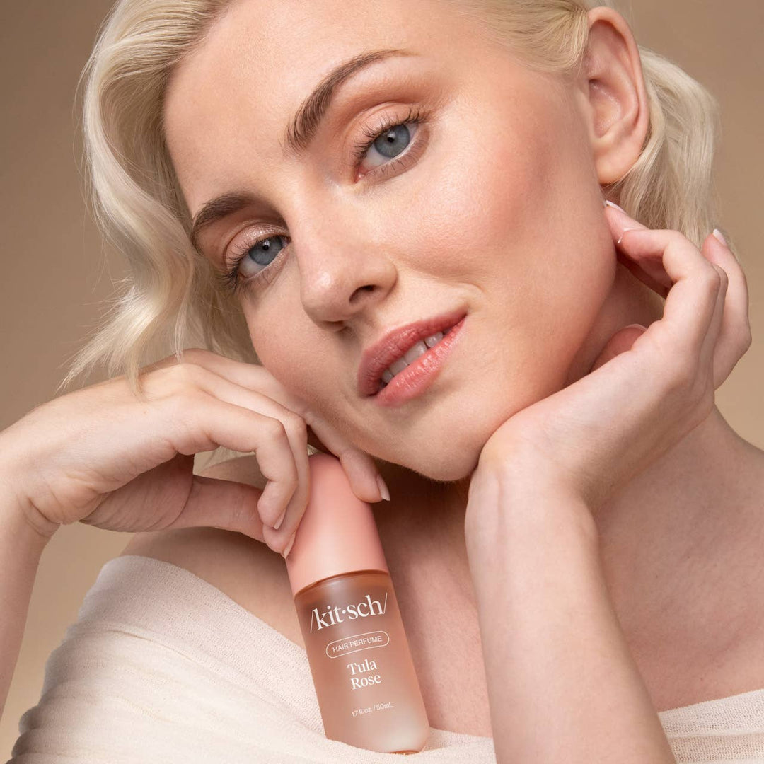 Woman holding a Kiehl's Tinted Rose product against a beige background