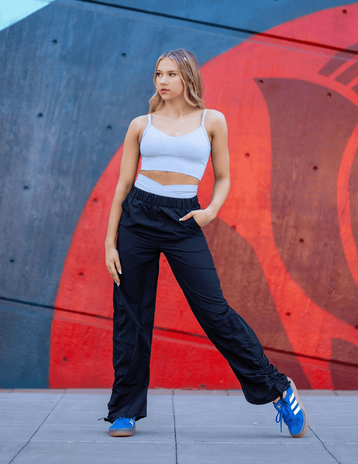 Woman in athletic wear standing against a colorful wall.