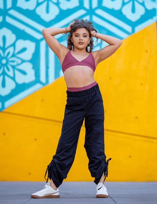 Person wearing a sports bra and high-waisted pants against a colorful wall.