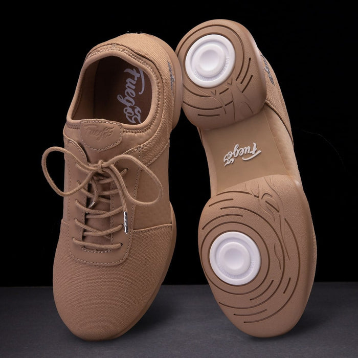Pair of tan dance shoes with white soles on a black background