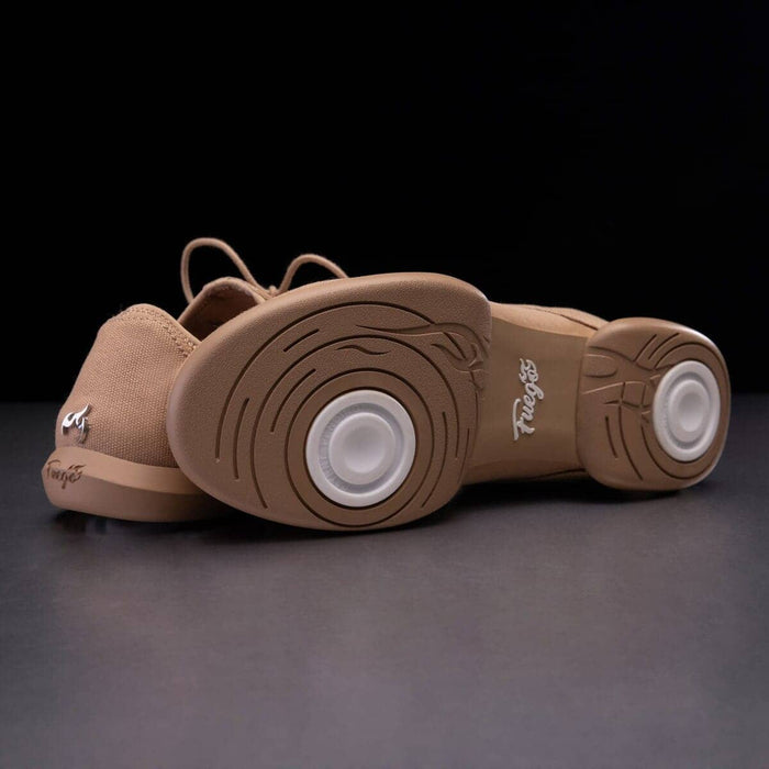 Tan dance shoes with white soles on a dark background