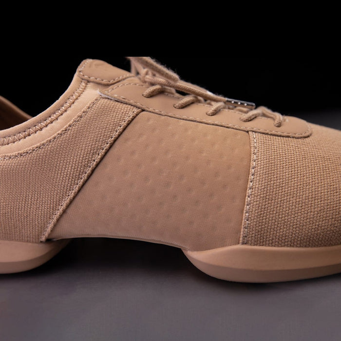 Tan sneaker with textured side panel on a dark background