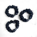 Three black scrunchies on a white background