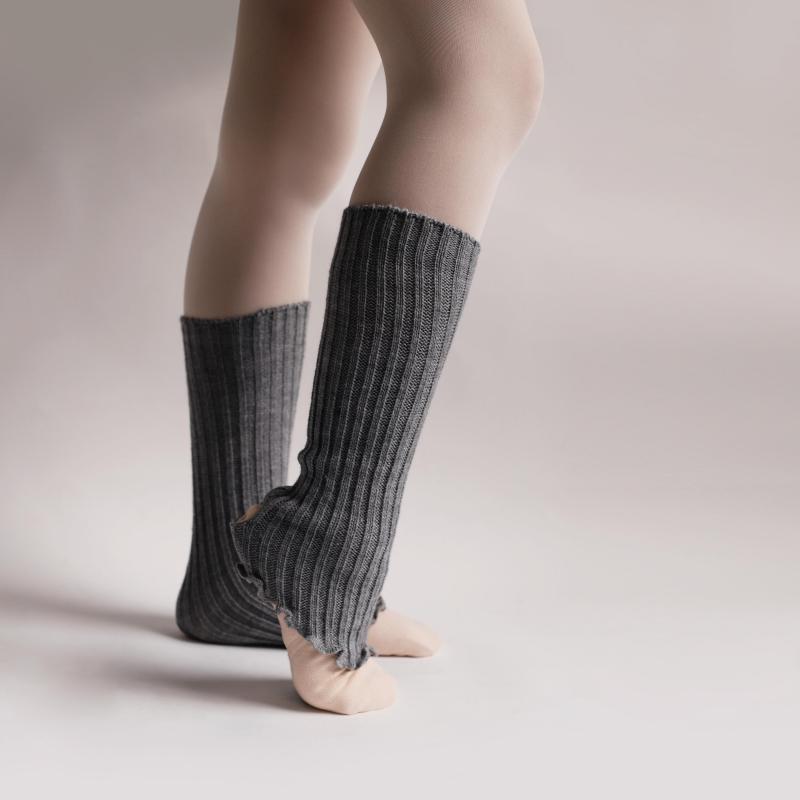 Person wearing gray ribbed knee-high socks on a plain background