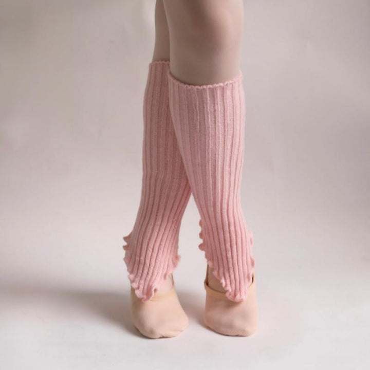 Pink ribbed leg warmers worn by a child on a plain background