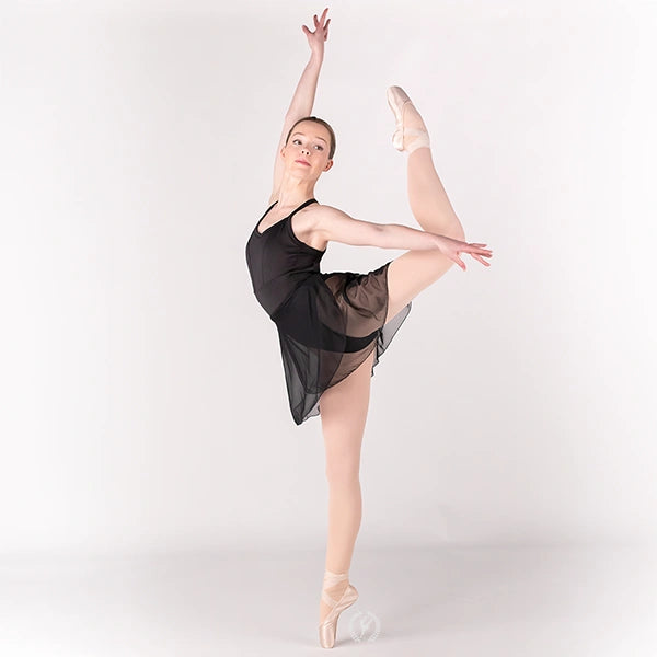 Ballerina in a black dress and pointe shoes posing on a white background