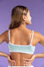 Woman wearing a light blue sports bra against a purple background