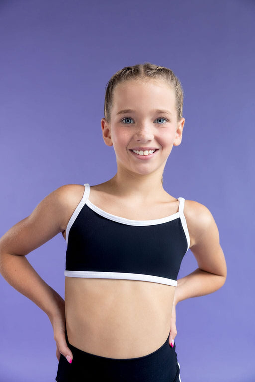 Young girl wearing a black sports bra with white trim against a purple background