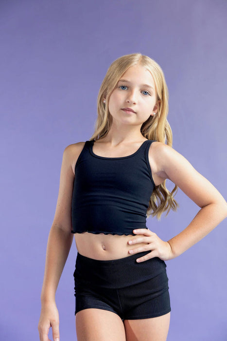 Young girl wearing a black sports bra and shorts against a purple background