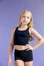 Young girl wearing a black sports bra and shorts against a purple background
