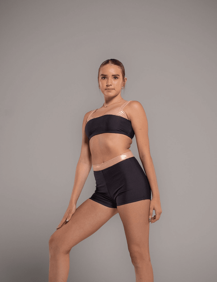 Woman wearing a black sports bra and shorts on a gray background