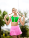 Woman in green and pink sports outfit with braided hair against a blurred natural background