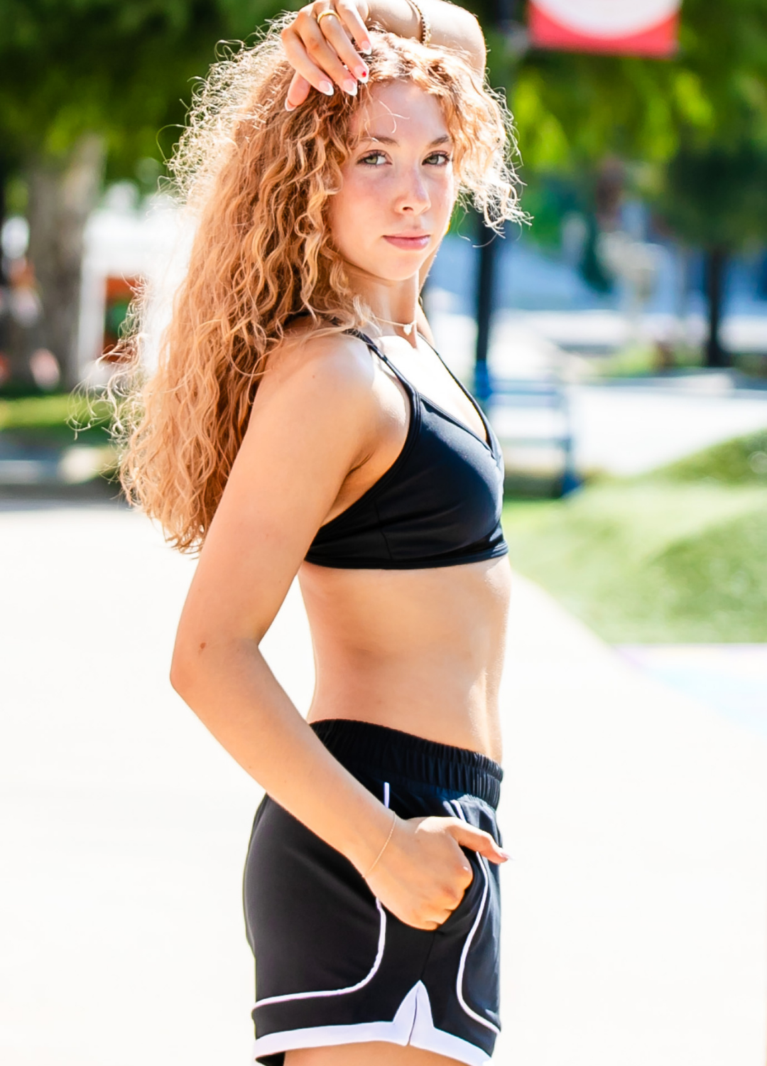 Woman in athletic wear standing outdoors with trees and a blurred background