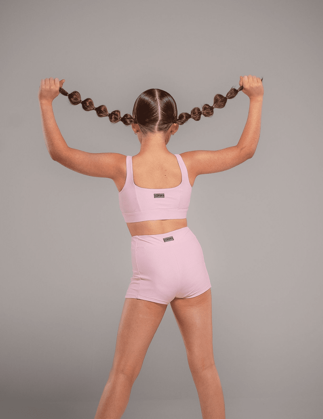 Person wearing a pink sports bra and shorts on a gray background
