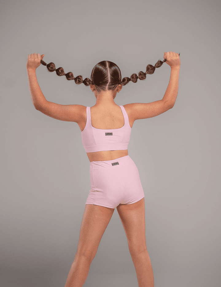 Person wearing a pink sports bra and shorts on a gray background