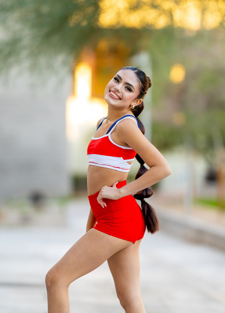 Woman in red athletic outfit standing outdoors with blurred background