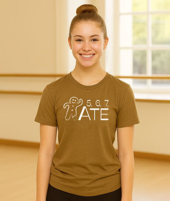 Person wearing a brown t-shirt with a graphic design in a room with a window.