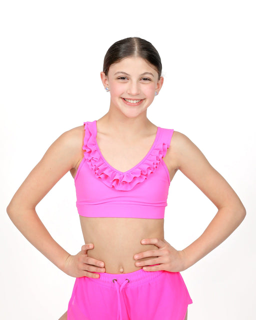 Young girl wearing a pink sports bra and shorts on a white background