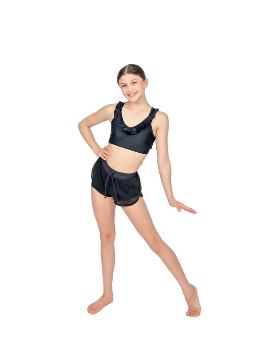 Young girl in a black dance outfit posing on a white background