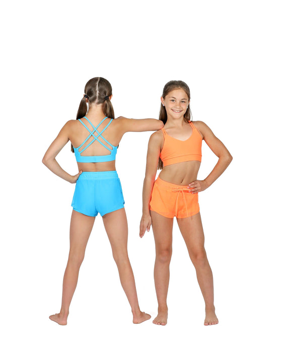Two girls wearing colorful sports bras and shorts on a white background