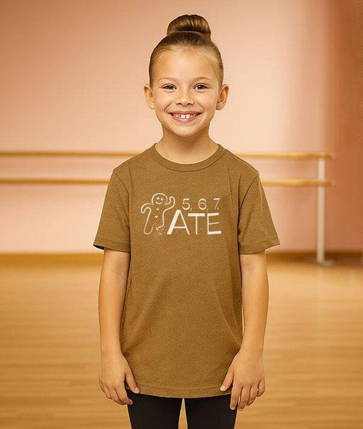 Young girl wearing a brown t-shirt with a graphic design in a dance studio.
