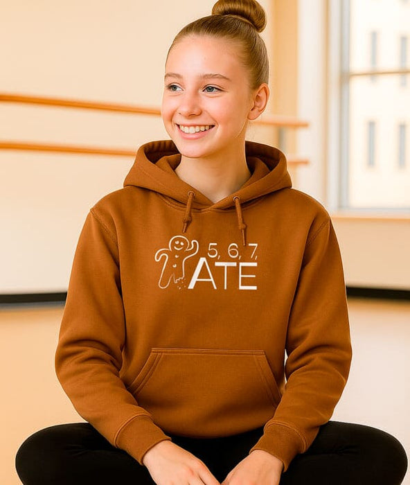 Person wearing a brown hoodie with a graphic design and text, sitting indoors.