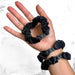 Hand holding three black scrunchies with a white marble background