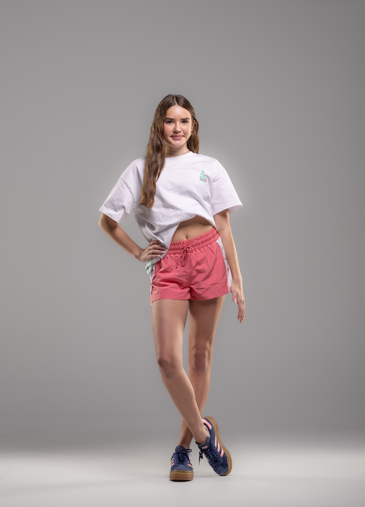 Woman wearing a white t-shirt and pink shorts on a gray background
