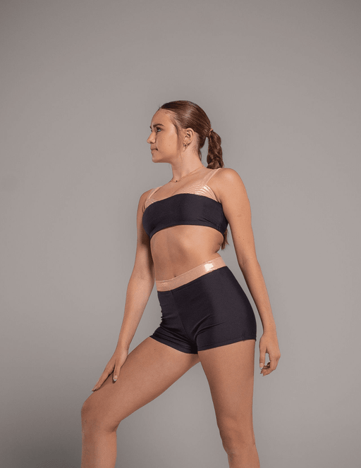Woman wearing a black sports bra and shorts on a gray background