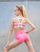 Woman wearing a pink sports bra and shorts with a gray background
