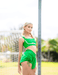 Woman wearing a green sports outfit on a blurred outdoor background